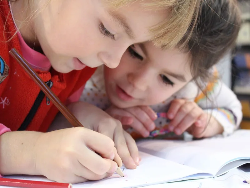 Two children drawing together at a table